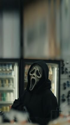 a person with a mask on in front of a refrigerator