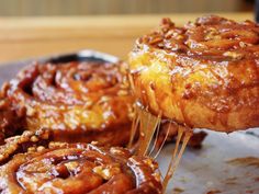 cinnamon buns are being held up by a fork with icing on them and drizzled with caramel