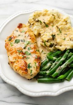 a white plate topped with chicken, mashed potatoes and green beans