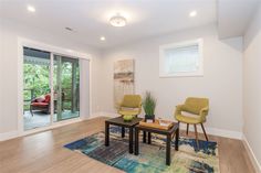 a living room with two chairs and a coffee table in front of a sliding glass door