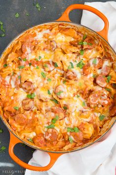 a casserole dish with sausage, cheese and parsley in an orange cast iron skillet