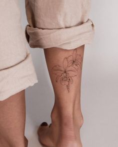 two people standing next to each other with tattoos on their legs and one has a flower tattooed on the lower leg