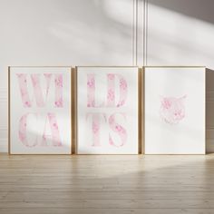 three pink and white art prints with the words wild cats on them in front of a wall