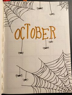 an open notebook with the word october written on it and spider's webs