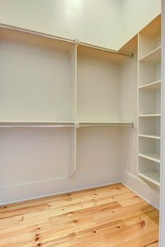 an empty walk in closet with white walls and wooden flooring on the hard wood floor