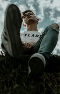 a man sitting on top of a grass covered field