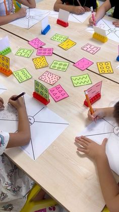 children are sitting at a table with paper and pencils on it as they draw shapes