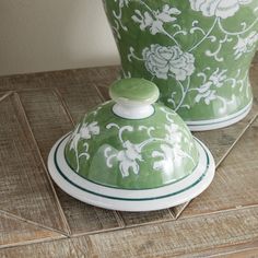 two green and white vases sitting on top of a wooden table next to each other