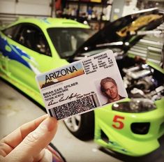 someone holding up a car id card in front of a green car