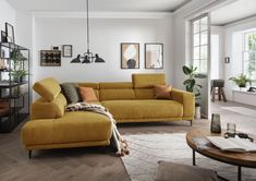 a living room with yellow couches and pictures on the wall above them, along with a coffee table