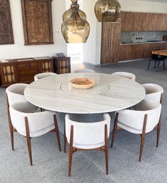 a dining room table with six chairs and a bowl on the top, in front of two hanging lights