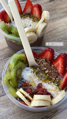 two bowls filled with granola, fruit and yogurt on top of a wooden table