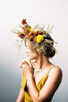 a woman in a yellow dress with flowers on her head and hands clasped to her chest