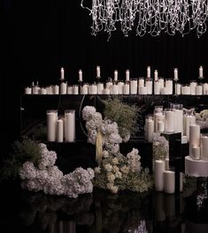 candles and flowers are arranged on the table in front of a chandelier that hangs from the ceiling