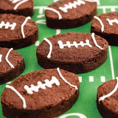 chocolate cookies decorated with white frosting and footballs on a green tablecloth, ready to be eaten