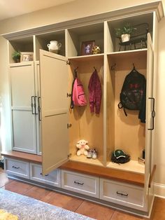 an entryway with two coats on the wall and some drawers in front of it