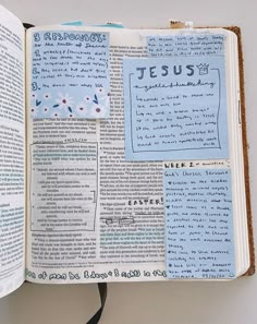 an open bible with blue and white paper on it's pages that read jesus