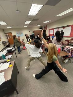 some people in a classroom doing different things with their hands and legs up to the ceiling