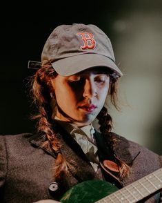 a woman wearing a baseball cap and holding a guitar