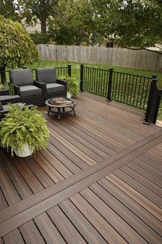 a wooden deck with chairs and plants on it