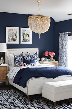 a bedroom decorated in blue and white with a chandelier hanging from the ceiling