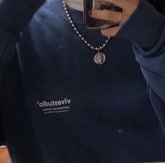 a person taking a selfie with their cell phone and wearing a blue sweatshirt that says vivestudio