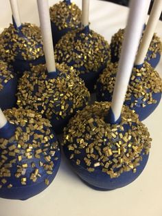 blue cake pops with gold sprinkles and white candles on a plate for dessert