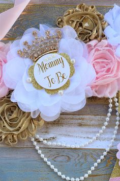 a close up of a piece of cloth with flowers on it and the words mommy to be written in gold