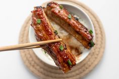 two skewered meats in a bowl with chopsticks on the side