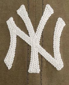 the letters k are written in crochet on top of a brown hat with white stitching