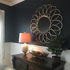 a living room with a table, lamp and mirror on it's side wall