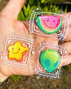 three stickers in the palm of someone's hand, each with different designs on them