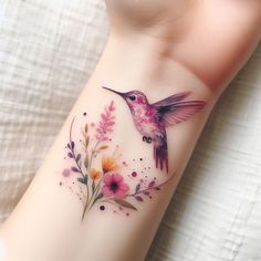 a hummingbird tattoo on the wrist with flowers