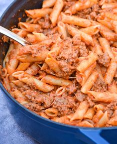 a skillet filled with pasta and meat sauce on top of a blue table cloth