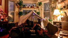 a tent is set up in the corner of a room with potted plants on the windowsill