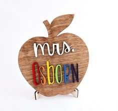 an apple shaped wooden sign with the word mus osporn spelled in multicolored letters