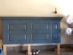 a blue headboard with two pairs of shoes on the floor in front of it