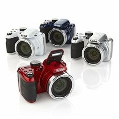 several different cameras sitting next to each other on a white surface and one is red