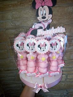 a person holding up a bunch of minnie mouse cupcakes