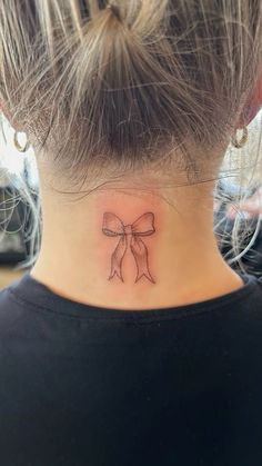 a woman's neck with a bow tattoo on it