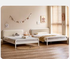 two beds in a room with wooden floors and white furniture, one has a teddy bear on the bed