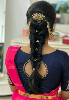 a woman with long black hair wearing a pink sari and gold jewelry on her neck