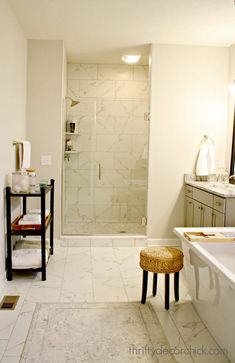 a white bathroom with marble flooring and large walk in shower next to a bathtub