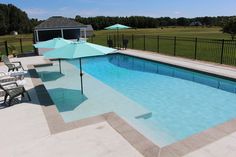 an empty swimming pool with chairs and umbrellas