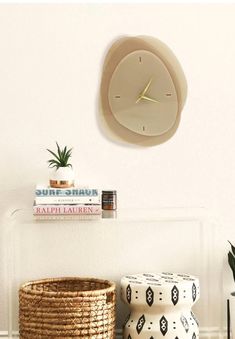 a white clock mounted to the side of a wall next to a wicker basket