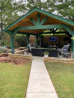 a covered patio with seating and grill in the back yard, next to a paved walkway