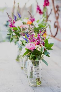 three vases filled with flowers sitting on top of a wooden table next to each other