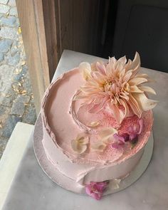 there is a pink cake with flowers on it