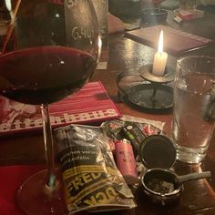 a glass of wine and some snacks on a table with a candle in the middle