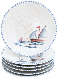 a stack of white and blue plates with sailboats on them in front of a clock